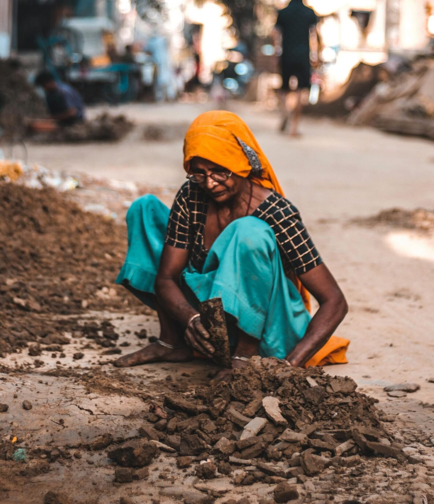 An Indian woman dressed in traditional attire working at a construction site on a city street.