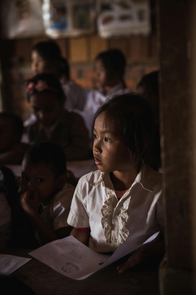 Focused children in a dimly lit classroom attentively listening and studying.